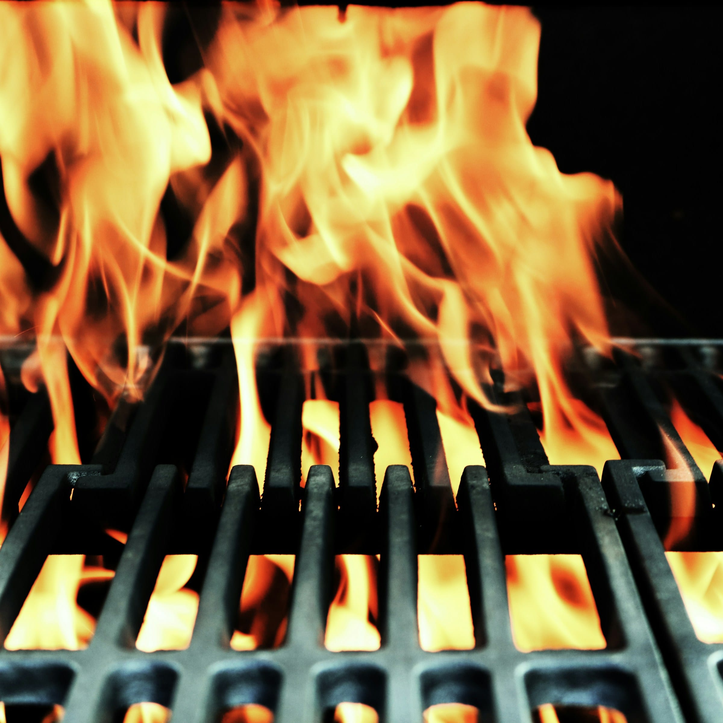 Open flame rising over grill grates